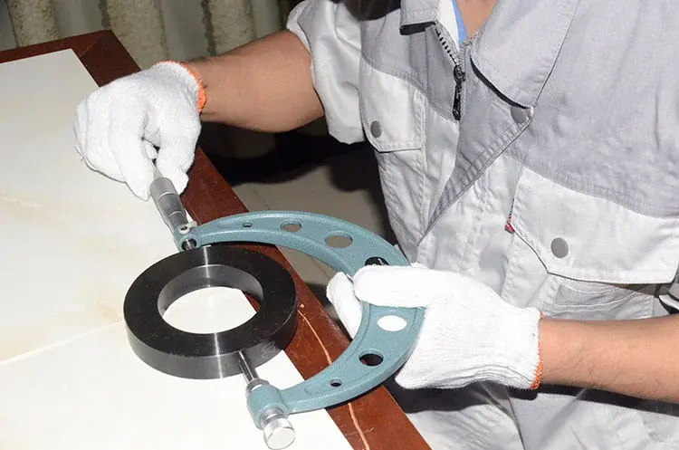 Gloved inspector measuring the outside diameter of a circular tool with a micrometer