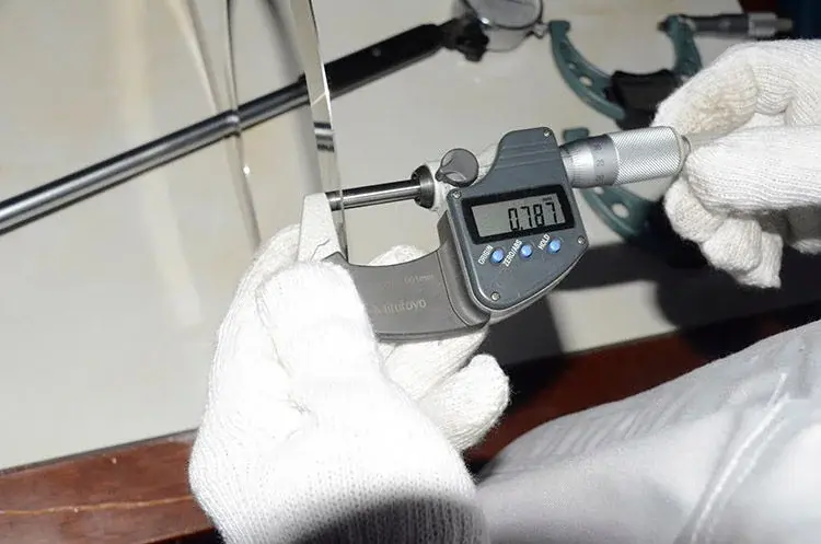 Inspector checking the thickness of a circular knife with a digital micrometer